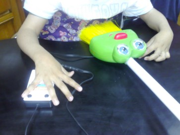 Imagem da m�o de uma crian�a a explorar a vasosura que fala com um touqe num man�pulo de press�o.