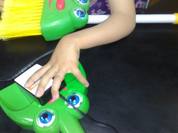 Outra Imagem da m�o de uma crian�a a explorar a vasosura que fala com um toque num man�pulo de press�o.